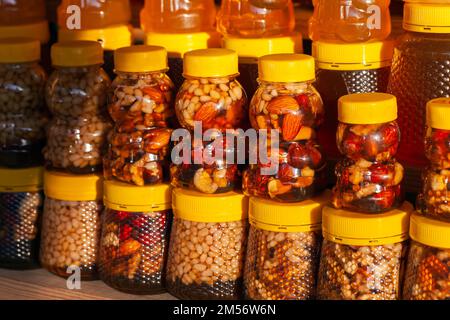 Assortiment de miel avec noix dans des pots en plastique. Gros plan avec mise au point douce sélective Banque D'Images