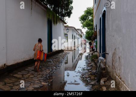Paraty, RJ, Brésil. 27 décembre 2012. Les gens marchent le long des rues pavées, partiellement inondées par la marée entrante, tandis qu'une calèche passe devant des bâtiments coloniaux dans le quartier du centre historique de Paraty, Rio de Janeiro, Brésil. Le centre historique de Paraty, ont été inscrits sur la liste du patrimoine mondial de l'UNESCO en 2019 sous le titre 'Paraty et Ilha Grande'. Banque D'Images