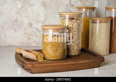 Panneau en bois avec pots de céréales sur table légère Banque D'Images