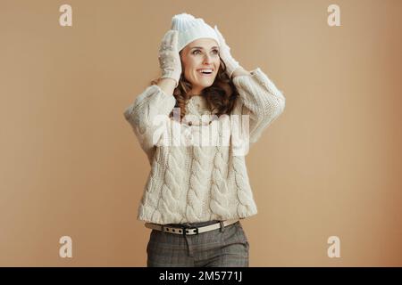 Bonjour hiver. surprise femme élégante en chandail beige, mitaines et chapeau sur fond beige. Banque D'Images