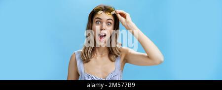 Une femme qui marche à travers le steet rencontre un ami qui prend des lunettes de soleil et regarde surpris de l'ouverture de la caméra bouche à dire salut avec large joyeux sourire et content Banque D'Images