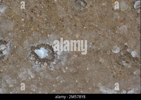 macro au-dessus de la vue d'une seule couche de sel de roche de fonte de glace sur le béton avec une couche gelée. Banque D'Images
