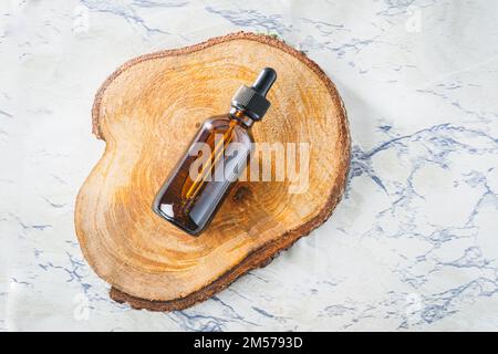 Vue de dessus d'une bouteille compte-gouttes d'huile essentielle sur un fond en bois découpé avec espace de copie Banque D'Images