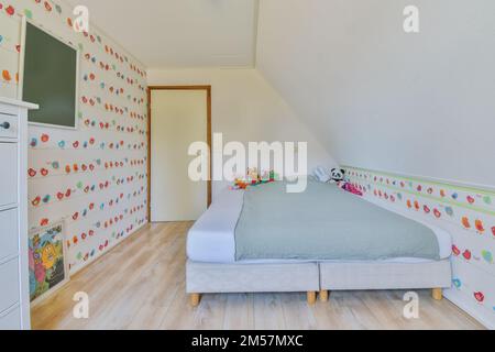 une chambre d'enfant avec des papiers peints colorés sur les murs et des meubles blancs devant le lit Banque D'Images