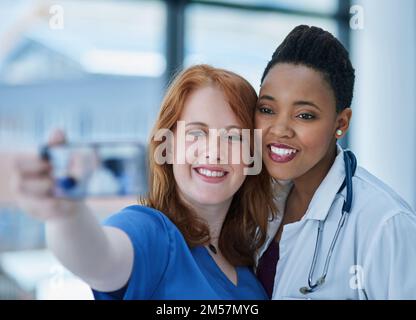 Les jeunes dans le domaine médical. deux jeunes médecins prenant un selfie ensemble. Banque D'Images