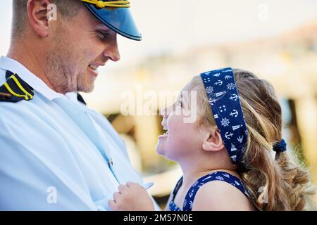 Pouvez-vous séjourner dans ce petit et mignon pour toujours ? un père dans un uniforme de marine liant avec sa petite fille sur le quai. Banque D'Images