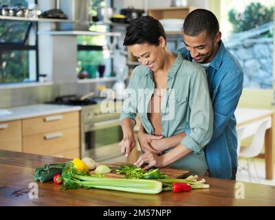 La nourriture faite avec amour a juste le goût meilleur. un jeune couple affectueux prépare un repas ensemble dans sa cuisine. Banque D'Images