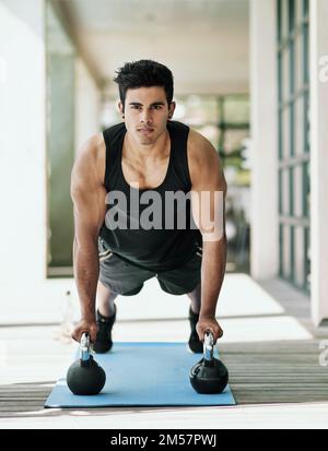 Réveillez-vous, faites de l'exercice. Portrait d'un jeune homme faisant des poussettes avec des haltères à la maison. Banque D'Images