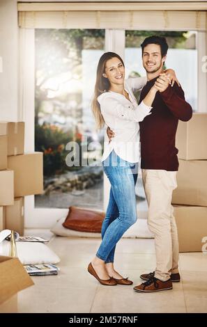 Acheter une maison ensemble est une grande affaire. Portrait complet d'un jeune couple affectueux qui danse tout en s'impassant dans une nouvelle maison. Banque D'Images