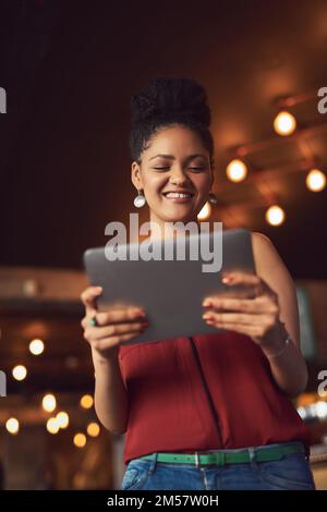 Découvrez les dernières nouveautés de son fil d'actualité pour aujourd'hui. une jeune femme utilisant une tablette numérique dans un café. Banque D'Images