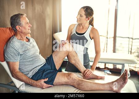 L'aider à devenir plus mobile. un homme âgé traité par un physiothérapeute. Banque D'Images