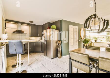 une cuisine, un coin repas et un salon dans une maison moderne avec un sol carrelé blanc et des murs verts sur le mur Banque D'Images