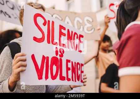 Des jeunes militants marchent contre la guerre et la violence dans les rues. Groupe de manifestants adolescents qui élèvent des affiches contre la violence pendant une paix et un r humain Banque D'Images