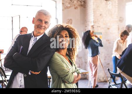 Deux collègues confiants regardant l'appareil photo souriant, les personnes réussies d'un démarrage créatif, portrait d'un collègue heureux Banque D'Images