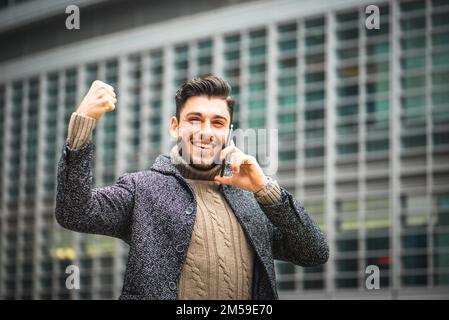 Jeune et intelligent homme d'affaires parlant sur le téléphone portable marchant dans le quartier du centre-ville, satisfait du travail fait, confiant gagnant homme d'affaires, décontracté Banque D'Images