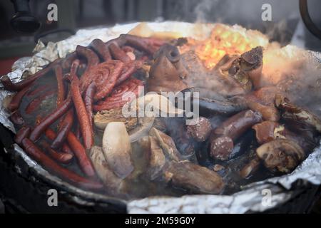 Dans un grand chou-fleur en fonte, la viande, les saucisses sont suspectées à la fête. Festivités de la rue. Banque D'Images