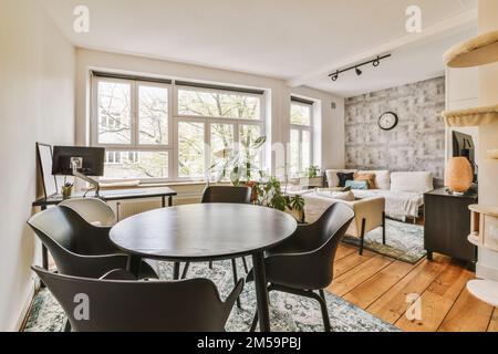 un salon avec des chaises et une table ronde devant la fenêtre donnant sur le jardin extérieur par une journée ensoleillée Banque D'Images