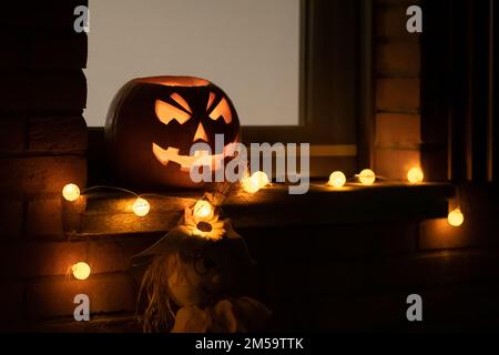Citrouille d'Halloween effrayante, lanterne Jack O avec lumières de citrouilles accrochées d'une fenêtre pendant une fête Banque D'Images