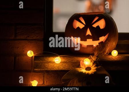 Citrouille d'Halloween effrayante, lanterne Jack O avec lumières de citrouilles accrochées d'une fenêtre pendant une fête Banque D'Images