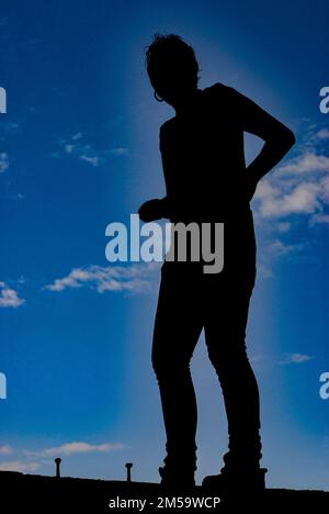 fille silhouetée sur fond bleu ciel Banque D'Images