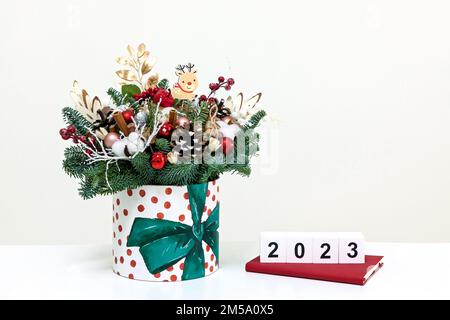 Bouquet du nouvel an de branches d'arbre de Noël, cônes, coton, jouets et cubes blancs avec les numéros 2023 sur fond blanc Banque D'Images