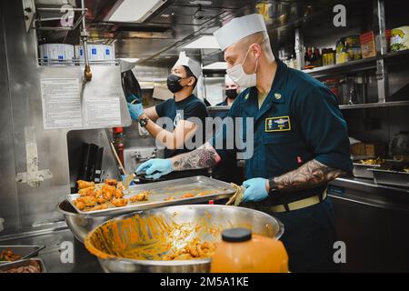 Le maître en chef de l'hôpital Zachary Silveus (en premier plan) et le spécialiste culinaire 3rd classe Joshua Geminiano (en arrière-plan) préparent la nourriture pour un événement récréatif à bord du destroyer à missiles guidés USS Momsen (DDG 92) alors qu'il est en cours dans l'océan Pacifique, au 13 février 2022. L'USS Momsen est actuellement déployé dans la zone d'opérations de la flotte américaine 3rd. Banque D'Images