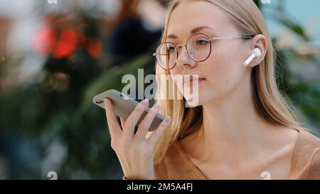 Gros plan affectif fille utiliser l'assistant virtuel parler dans le microphone du téléphone caucasien jeune dame avec des lunettes parler sur le haut-parleur enregistrer message audio Banque D'Images