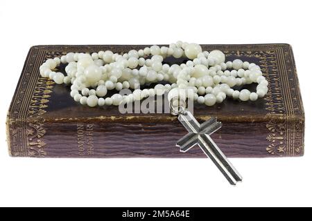 rosary sur un livre de prière commun vintage isolé sur fond blanc Banque D'Images