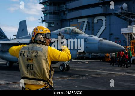 MER DES PHILIPPINES (fév 15, 2022) US Navy Aviation Boatswain's Mate (Handling) 1st classe Daniel Suggs, de Killeen, Texas, avec le porte-avions de la classe Nimitz USS Abraham Lincoln (CVN 72) dirige un F/A-18E Super Hornet, affecté aux “vigilantes” de l'Escadron de chasseurs Strike (VFA) 151, pendant les opérations de vol à l'appui de l'exercice Jungle Warfare 22 (JWX 22) à travers Okinawa, Japon. JWX 22 est un exercice de formation sur le terrain à grande échelle axé sur l'exploitation des capacités intégrées des partenaires communs et alliés afin de renforcer la sensibilisation, la manœuvre et les incendies de tous les domaines dans un maritim distribué Banque D'Images