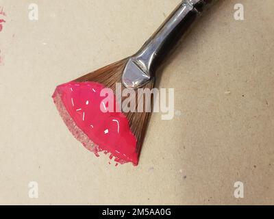 Vue de dessus d'un pinceau trempé dans de la peinture rose sur la surface beige Banque D'Images