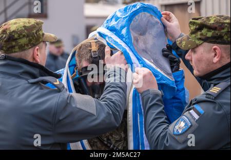 Deux membres des forces armées estoniennes aident un membre des forces armées lettones à retirer son équipement de protection personnelle lors d'un cours sur les matières dangereuses de l'escadron de construction et d'entraînement de 435th dans le complexe d'entraînement du CTS 435, base aérienne de Ramstein, Allemagne, le 15 février 2022. Les membres des forces armées des États baltes ont pratiqué des processus de décontamination qui se produisaient s’ils étaient exposés à des matières dangereuses. Après avoir terminé le cours, les membres ont été certifiés pour l'utilisation appropriée de l'équipement HAZMAT. Banque D'Images