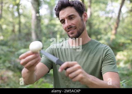 un jeune homme dans la forêt contient un champignon Banque D'Images