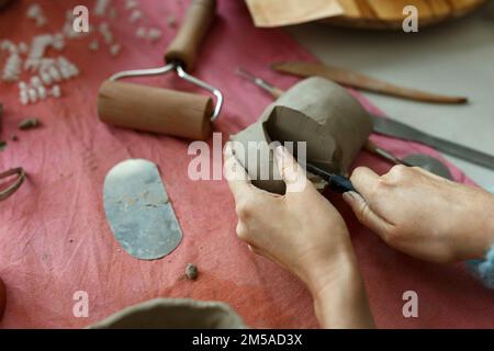 Maître Potter adulte coupant l'argile sur la table. Vue de dessus, gros plan, mains seulement. Art et affaires, passe-temps et concept de travail indépendant Banque D'Images