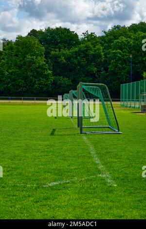 regardez plusieurs petits buts de football depuis la marge d'un terrain de jeu vert Banque D'Images