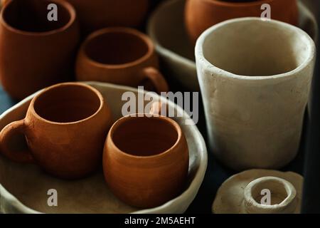 Un gros plan de divers vaisselle en argile séchante sur une étagère. Un concept de studio de poterie. Plats artisanaux, bols, pots, mugs de différentes couleurs. Vue confortable Banque D'Images