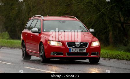 2013 voiture de domaine Volvo V70 rouge conduite sous la pluie avec phares allumés Banque D'Images