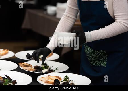 chef servant des moules dans une sauce au vin blanc et des toasts de pain blanc Banque D'Images