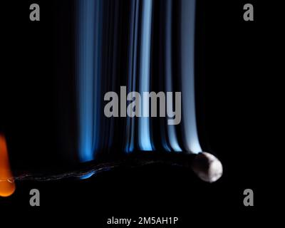 Allumette brûlée avec des jets de fumée blancs qui se levent isolés sur un fond noir Banque D'Images