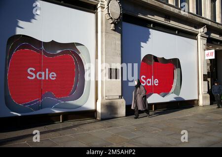 Un acheteur passe devant une vitrine sur Oxford Street à Londres alors que la vente du lendemain de Noël traditionnel commence. En raison de la crise du coût de la vie, les ventes en ligne ont commencé dès que les détaillants s'attendent à une baisse des ventes au détail. Banque D'Images