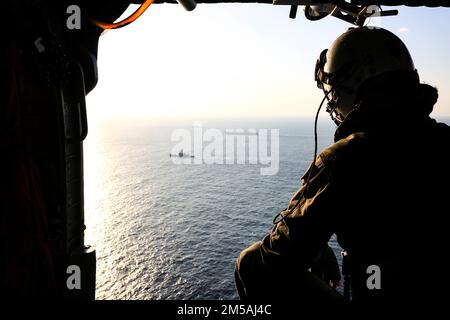 MER DES PHILIPPINES (fév 16, 2022) Spécialiste en communication de masse de la Marine américaine 3rd classe Lake Fultz, de Newport, en Oregon, observe le porte-avions de classe Nimitz USS Abraham Lincoln (CVN 72), le croiseur de missiles guidés de classe Ticonderoga USS Mobile Bay (CG 53) et le destroyer de missiles guidés de classe Arleigh Burke USS Spruance (DDG 111) Naviguez en formation avec la Force d'autodéfense maritime du Japon (JMSDF) le destroyer de la classe Murasame JS Inazuma (DD 105) et la classe Hatakaze JS Hatakaze (TV [Training Vessel] 3520) pendant l'exercice Jungle Warfare 2022 (JWX 22) à partir de la cabine d'un hélicoptère MH-60s Sea Hawk, affecté au Banque D'Images