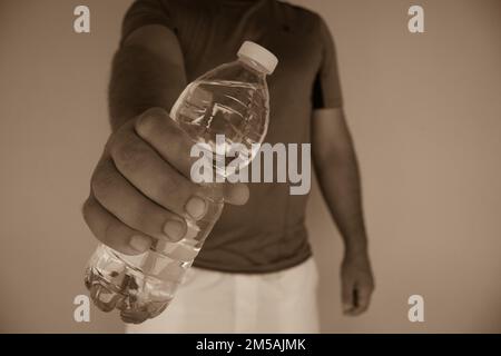 Image des mains d'un homme ouvrant une bouteille d'eau après avoir fait du sport. Réhydratation du corps Banque D'Images