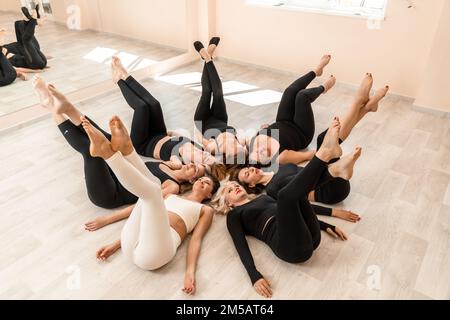 Sept femmes heureuses se trouvent sur le dos, sur le sol, la tête étant pressée. Banque D'Images