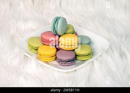 Macarons français colorés sur une assiette carrée blanche et une fourrure Banque D'Images