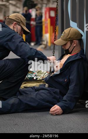 220215-N-MH210-1049 NORFOLK, VIRGINIE. (17 février 2022) - Un marin affecté au navire d'assaut amphibie USS Bataan (LHD 5), traite une blessure simulée lors d'un exercice de masse dans la baie hangar le 17 février 2022. Bataan est à la base navale de Norfolk. Banque D'Images