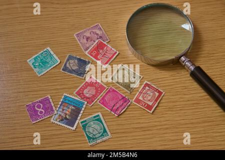 Plat de quelques anciens timbres de différents pays du monde à côté d'une loupe pour un fan philatélique Banque D'Images