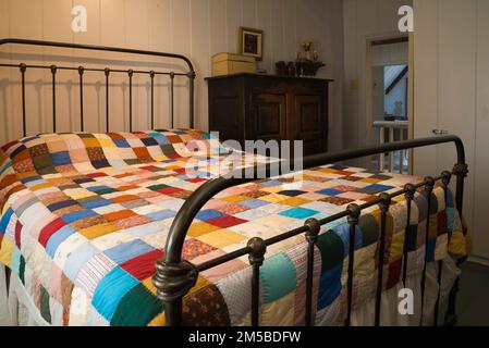 Ancien lit double en laiton recouvert de patchwork dans la chambre d'hôtes principale à l'étage à l'intérieur de la maison de style français 1772. Banque D'Images