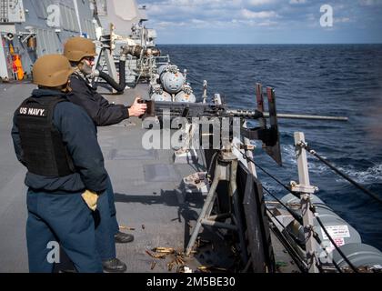 MER DE CHINE ORIENTALE (21 février 2022) Günner’s Mate 2nd Class Christian Martinez, à gauche, de New York City, joue le rôle d’instructeur d’armes à service d’équipage pour Gunner’s Mate 2nd Class Trevor Felker, d’Alliance, Nebraska, Pendant qu'il tire la mitrailleuse de calibre .50 lors d'une qualification d'armes à bord du destroyer guidé de classe Arleigh Burke USS Dewey (DDG 105). Dewey est affecté au Destroyer Squadron (DESRON) 15 et est en cours de soutien à un Indo-Pacific libre et ouvert. CTF 71/DESRON 15 est la plus importante force de surface déployée par la Marine et la principale force de surface de la flotte américaine 7th. Banque D'Images