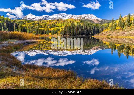 Le lac Calm Woods, dans la forêt nationale d'Uncompahgre, près de Telluride, Colorado, se reflète sur les sommets Dolores et Middle Peak enneigés. Banque D'Images