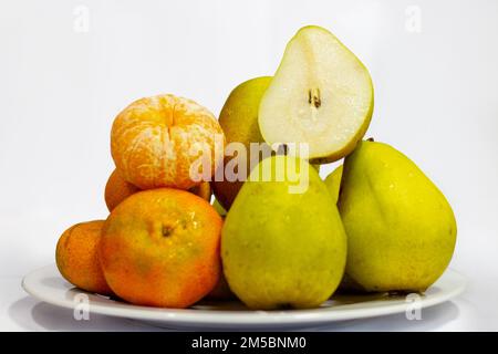 plusieurs mandarines et plusieurs poires sur une assiette blanche Banque D'Images