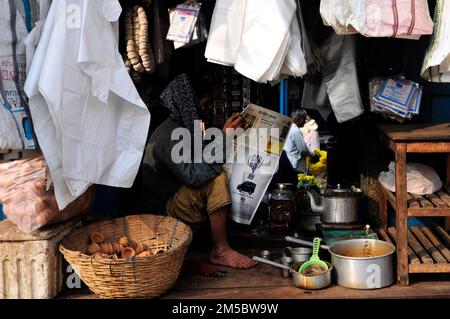 Un homme bengali lisant le journal du matin sur le marché de Kolkata, en Inde. Banque D'Images